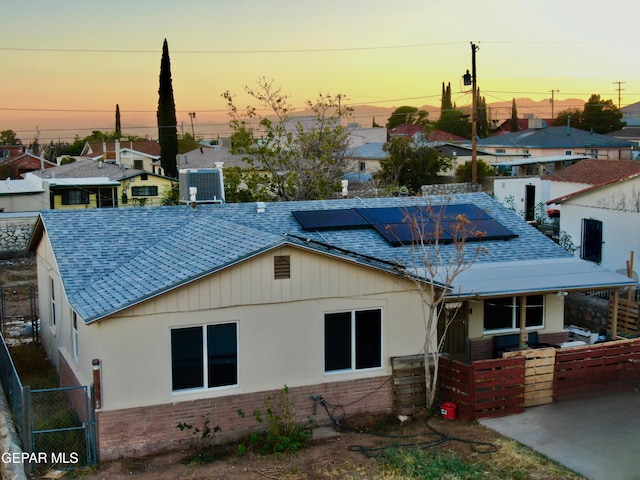 back house at dusk featuring central air condition unit and solar panels