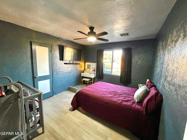 bedroom with access to exterior, wood-type flooring, a textured ceiling, and ceiling fan