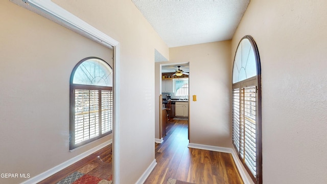 corridor with dark hardwood / wood-style floors and a textured ceiling