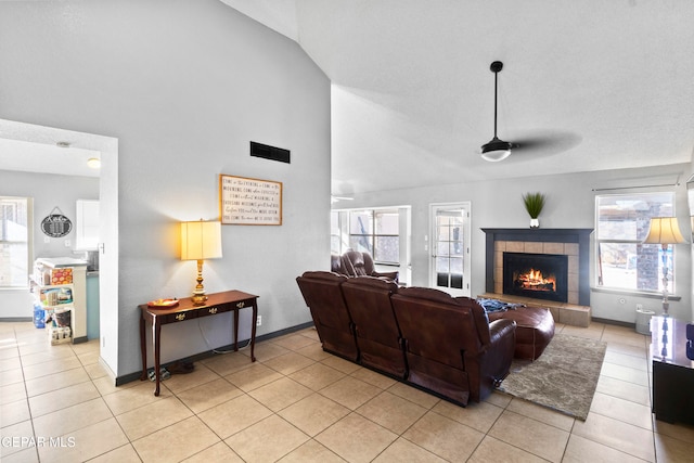 tiled living room featuring ceiling fan, lofted ceiling, and a tile fireplace