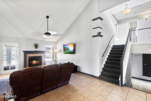 tiled living room featuring a tile fireplace, high vaulted ceiling, and ceiling fan