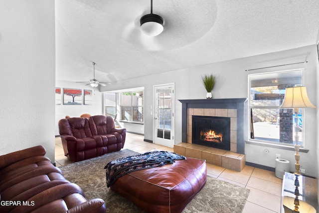 tiled living room with lofted ceiling, a fireplace, ceiling fan, and a textured ceiling