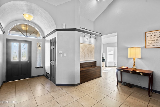 tiled entryway featuring lofted ceiling and a textured ceiling