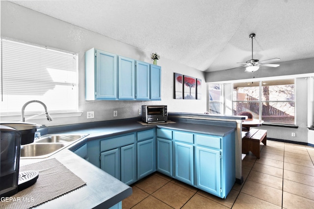 kitchen featuring blue cabinetry, a textured ceiling, tile patterned floors, and sink