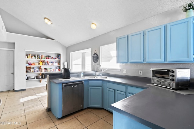 kitchen with vaulted ceiling, sink, blue cabinetry, light tile patterned floors, and dishwasher