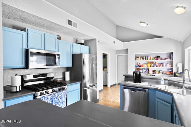 kitchen featuring blue cabinets, sink, vaulted ceiling, light tile patterned floors, and stainless steel appliances