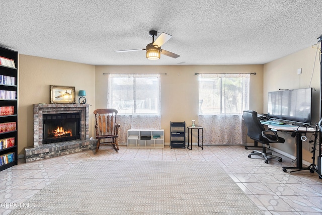 office featuring ceiling fan, a fireplace, light tile patterned floors, and a textured ceiling