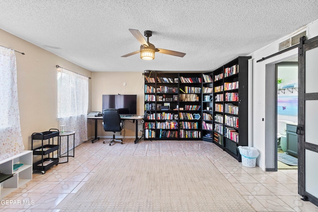 office area with a barn door, light tile patterned floors, and a textured ceiling