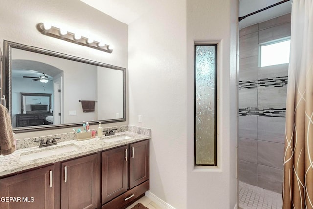 bathroom with tiled shower, vanity, and ceiling fan