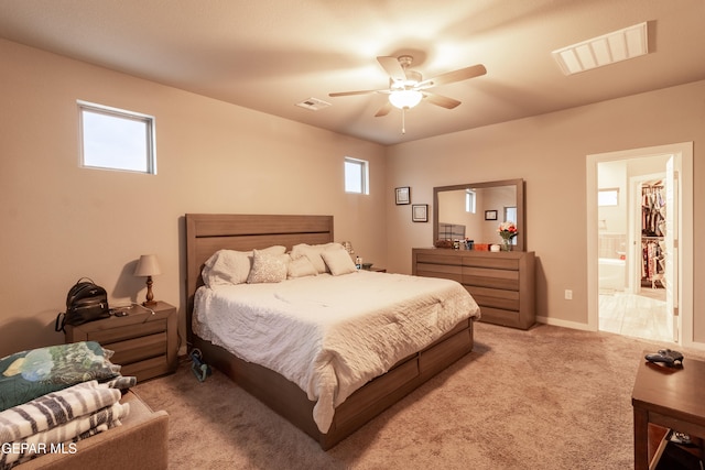 carpeted bedroom featuring a walk in closet, multiple windows, and ceiling fan