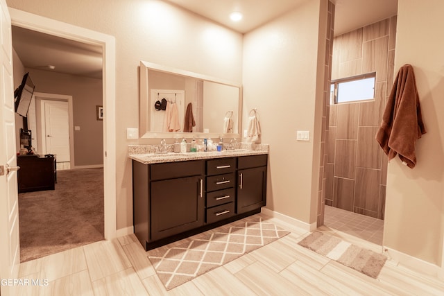 bathroom featuring tile patterned flooring, vanity, and tiled shower