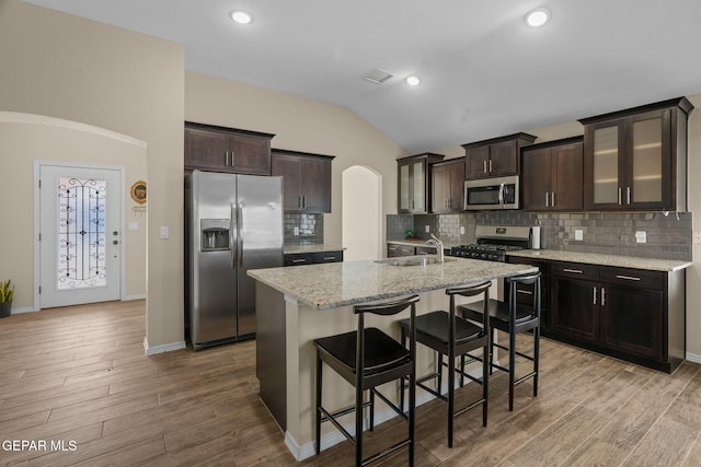 kitchen featuring lofted ceiling, a center island with sink, sink, light hardwood / wood-style flooring, and stainless steel appliances