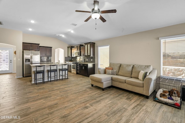 living room featuring ceiling fan, sink, wood-type flooring, and lofted ceiling