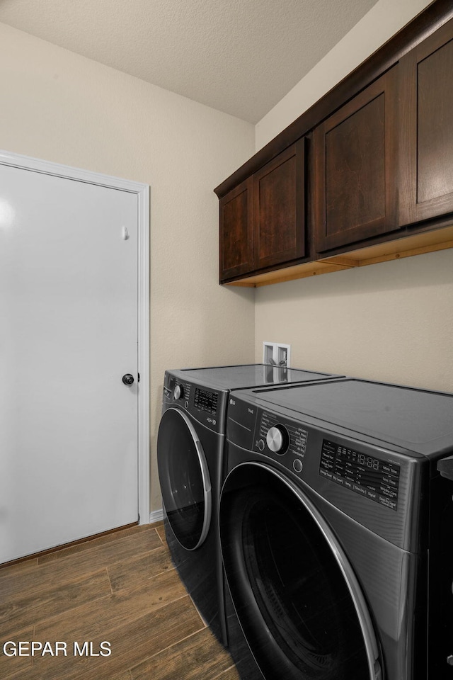 washroom featuring a textured ceiling, cabinets, separate washer and dryer, and dark wood-type flooring