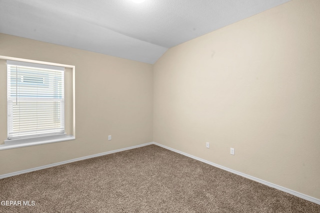 empty room featuring carpet, lofted ceiling, and a textured ceiling