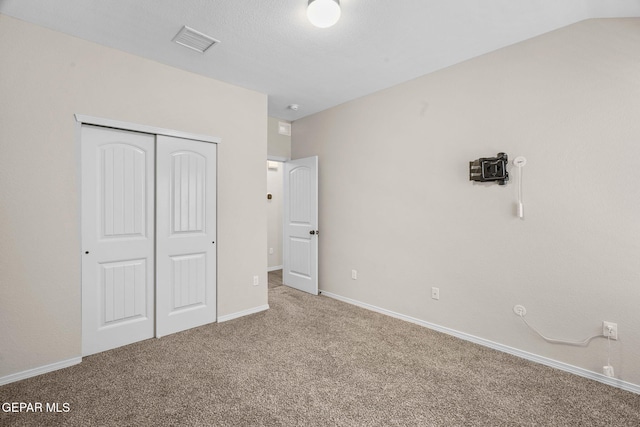 unfurnished bedroom featuring a closet, carpet floors, and lofted ceiling