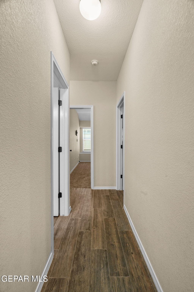 hallway featuring dark hardwood / wood-style floors and a textured ceiling