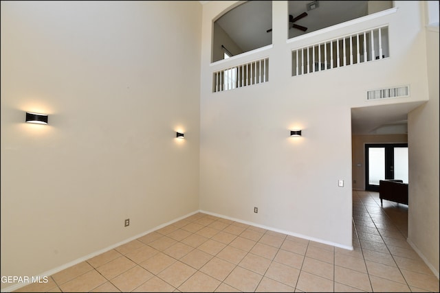 tiled empty room with high vaulted ceiling and ceiling fan