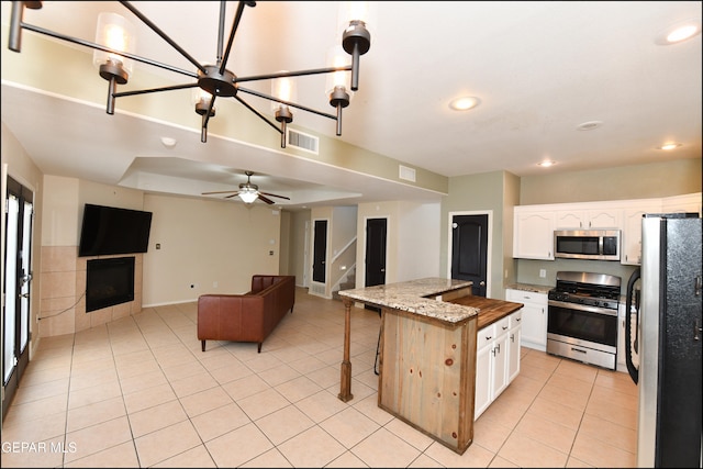 kitchen with white cabinetry, a center island, stainless steel appliances, light stone counters, and a breakfast bar area