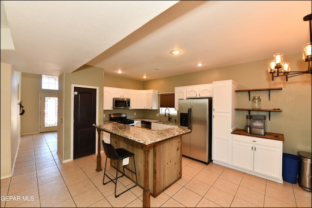 kitchen with light tile patterned floors, dark stone countertops, white cabinetry, and appliances with stainless steel finishes