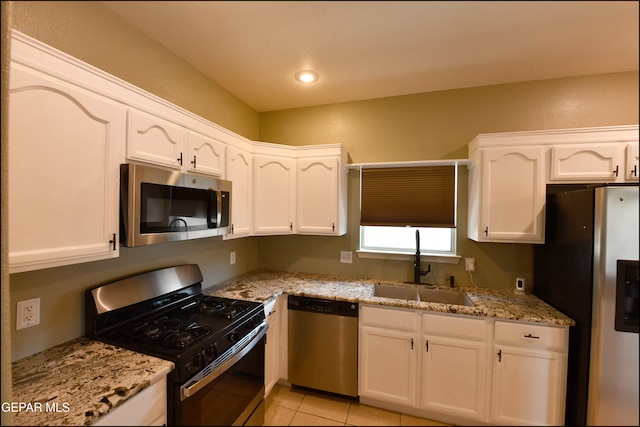 kitchen with white cabinets, appliances with stainless steel finishes, light stone counters, and sink