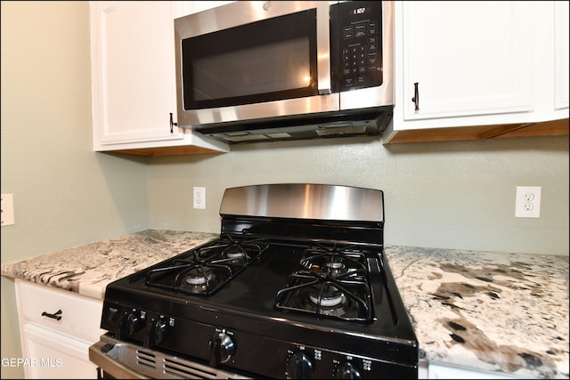 kitchen with black gas stove, white cabinetry, and light stone counters