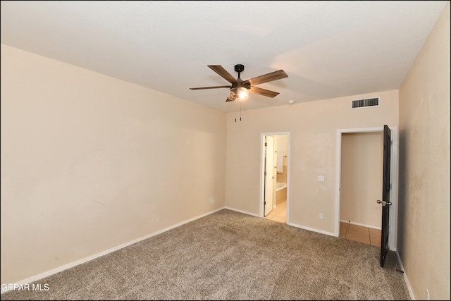 unfurnished bedroom with ceiling fan, light carpet, and ensuite bath