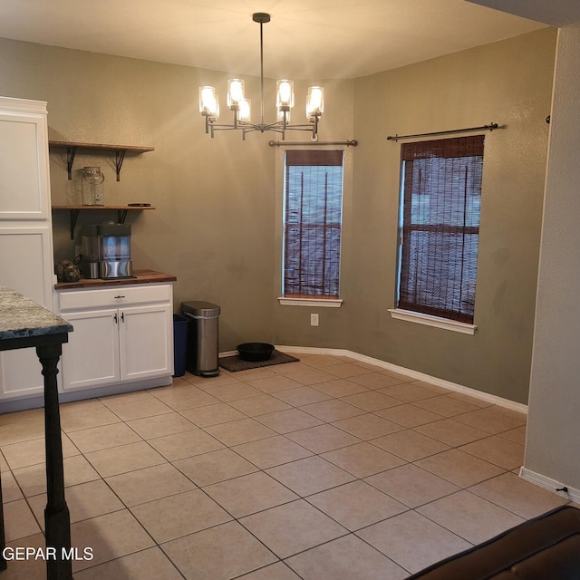 unfurnished dining area with light tile patterned floors and an inviting chandelier