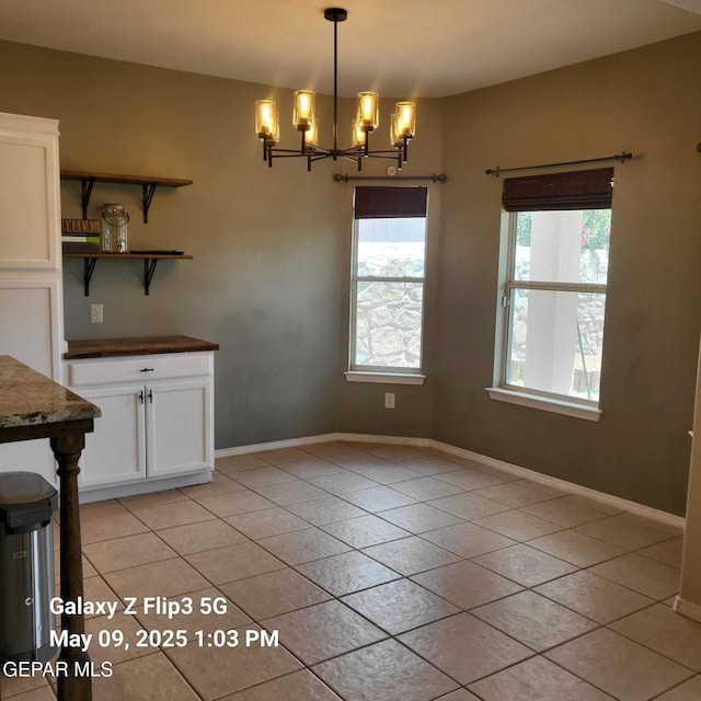 12712 Tierra Aurora Dr, El Paso, TX 79938 - unfurnished dining area featuring a chandelier, light tile patterned floors, and baseboards