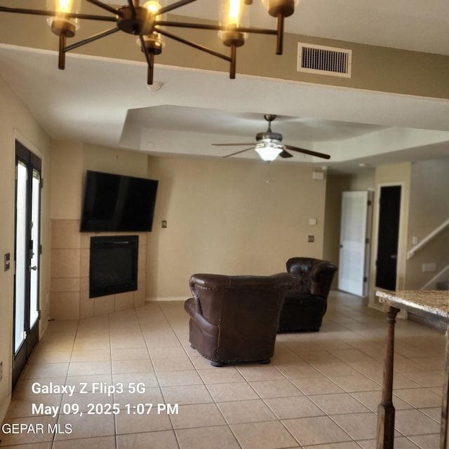 12712 Tierra Aurora Dr, El Paso, TX 79938 - living room featuring a tile fireplace, light tile patterned flooring, and a raised ceiling