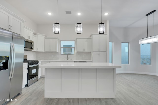 kitchen with white cabinetry, appliances with stainless steel finishes, a center island, and pendant lighting