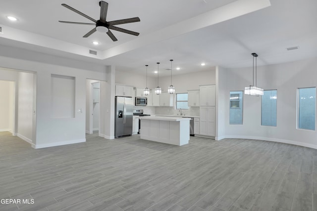 kitchen with stainless steel appliances, decorative light fixtures, a center island, and white cabinets