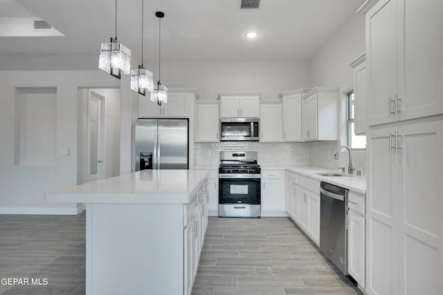 kitchen with a kitchen island, white cabinetry, sink, backsplash, and stainless steel appliances