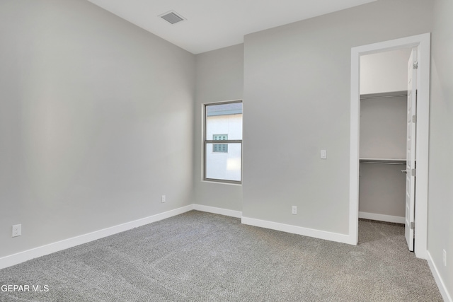 unfurnished bedroom featuring a walk in closet, carpet flooring, and a closet