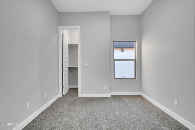 unfurnished bedroom with a closet, a spacious closet, and carpet flooring