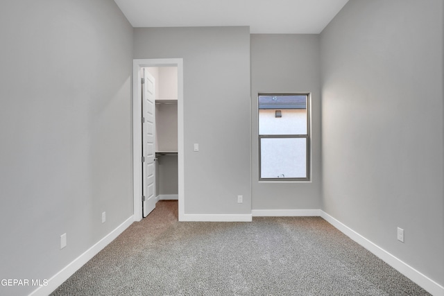 unfurnished bedroom with a closet, a spacious closet, and carpet