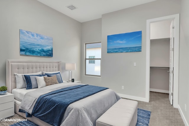 carpeted bedroom featuring visible vents, baseboards, a closet, and a walk in closet