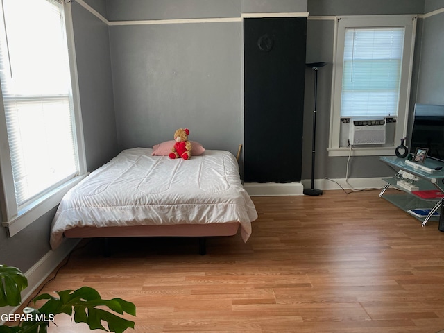 bedroom with light wood-type flooring, multiple windows, and cooling unit