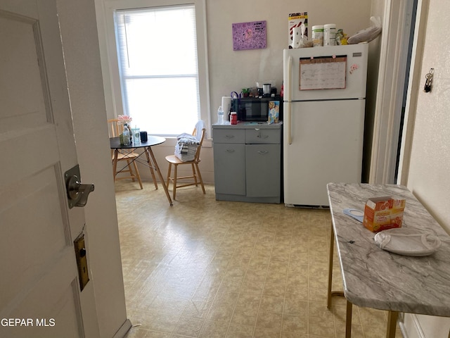 kitchen with white fridge, gray cabinets, and light hardwood / wood-style flooring