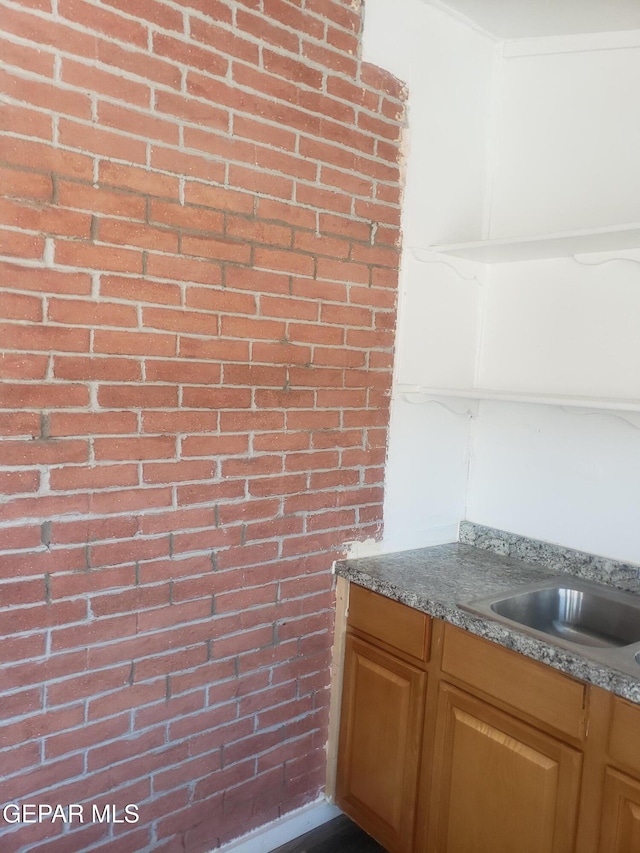 interior space featuring stone counters, sink, and brick wall