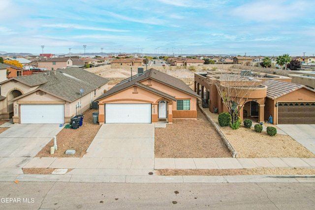 view of front of home featuring a garage, concrete driveway, a residential view, and stucco siding