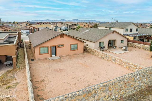 view of front of house featuring a patio, a fenced backyard, a residential view, a mountain view, and stucco siding