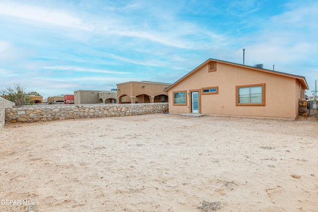 rear view of house with fence and stucco siding