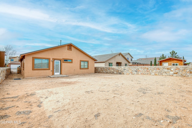 rear view of house featuring a fenced backyard and stucco siding