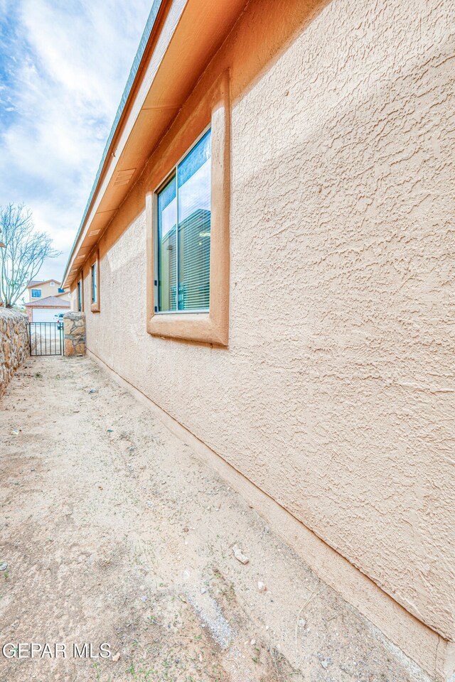 view of side of home featuring fence and stucco siding