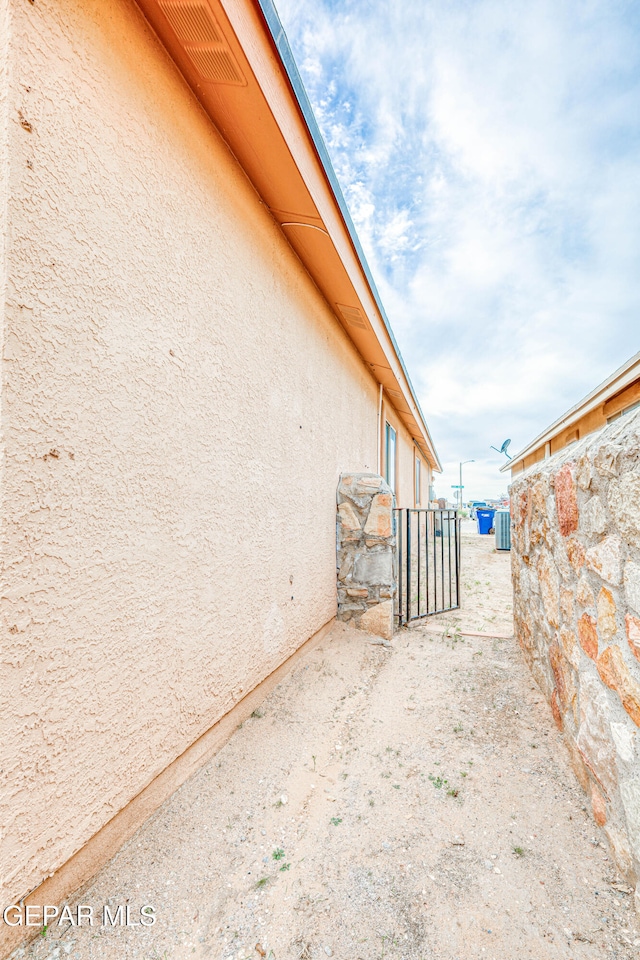 view of property exterior featuring central AC, a gate, and stucco siding