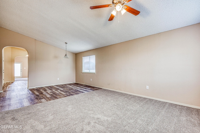 empty room featuring arched walkways, ceiling fan, a textured ceiling, lofted ceiling, and carpet flooring