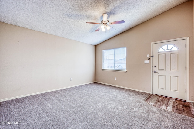 carpeted entryway with lofted ceiling, ceiling fan, a textured ceiling, and baseboards