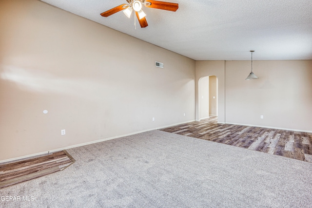 unfurnished room with visible vents, arched walkways, ceiling fan, carpet, and a textured ceiling