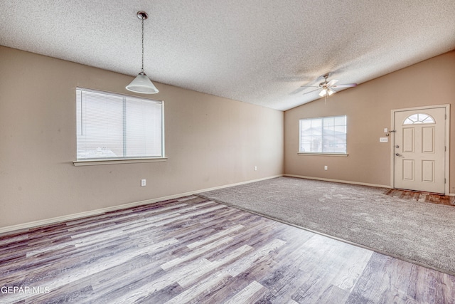 spare room with baseboards, a ceiling fan, lofted ceiling, wood finished floors, and a textured ceiling